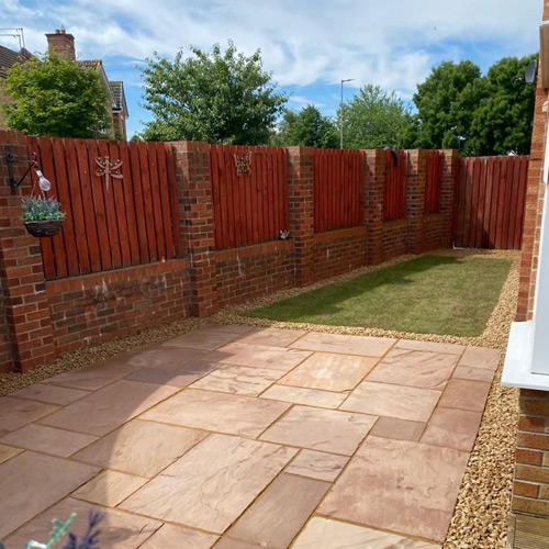 Indian sandstone patio with brick walling and gravel border