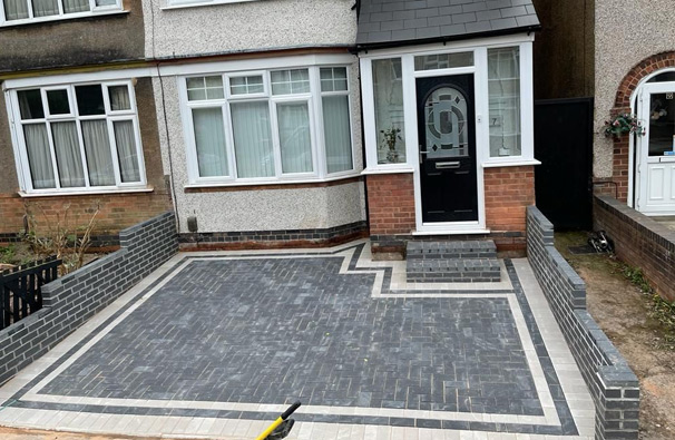 Charcoal block paved driveway with a light border and brick walls